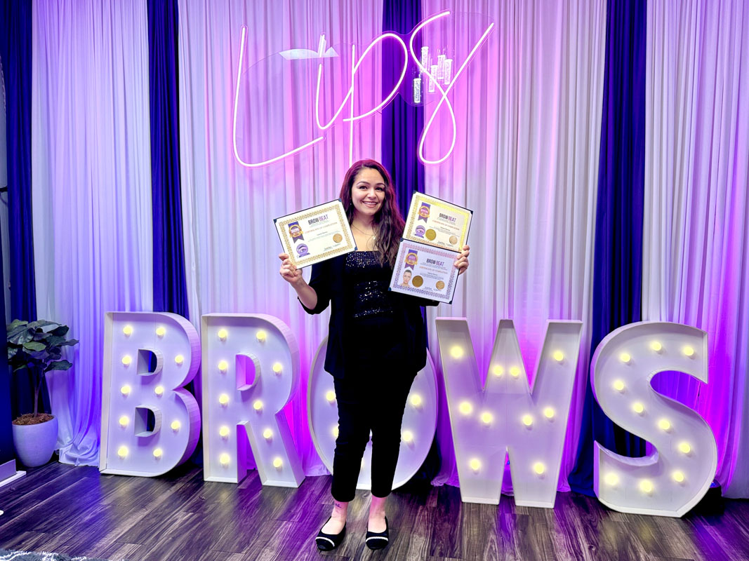 Student proudly holding brow certification after 3-in-1 course Beginner student smiling with certificate in classroom