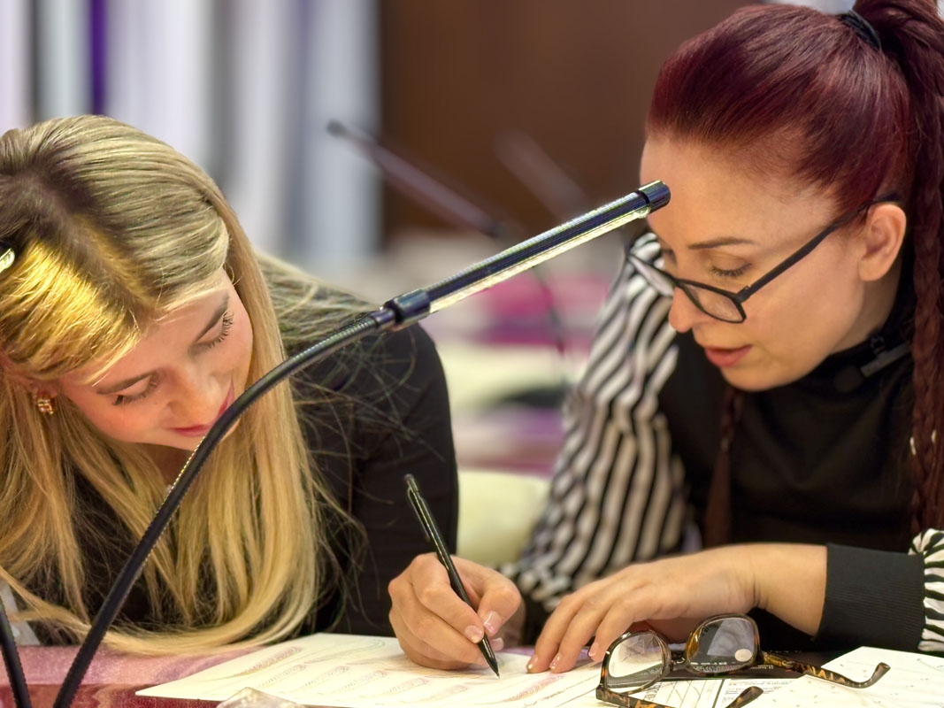 Paper exercise for microblading strokes in hands-on training Student repeating microblading strokes on lined paper sheet