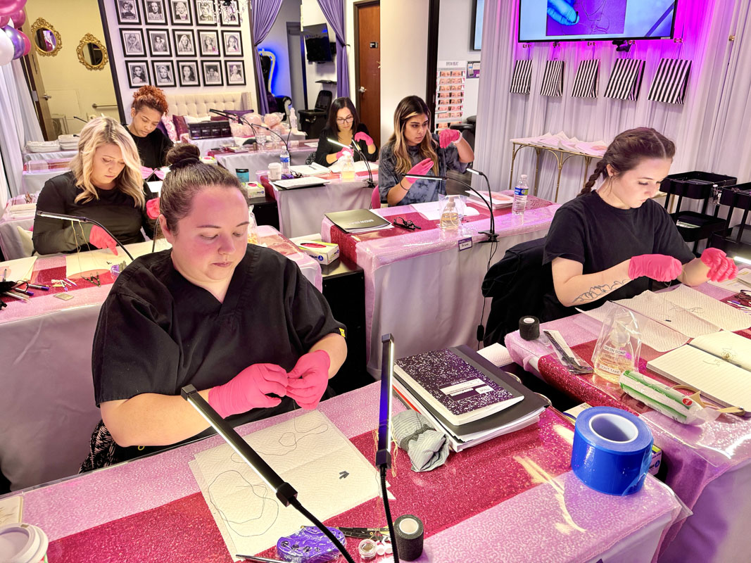 Student preparing mapping string with pigment before brow mapping Close-up of student inking mapping string to prepare for brow mapping exercise in class