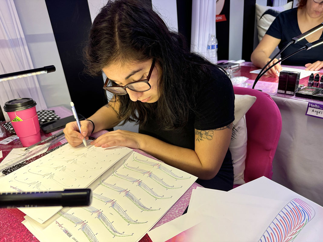 Paper practice sheets included in certification course cost Students repeating microblading strokes on paper in class